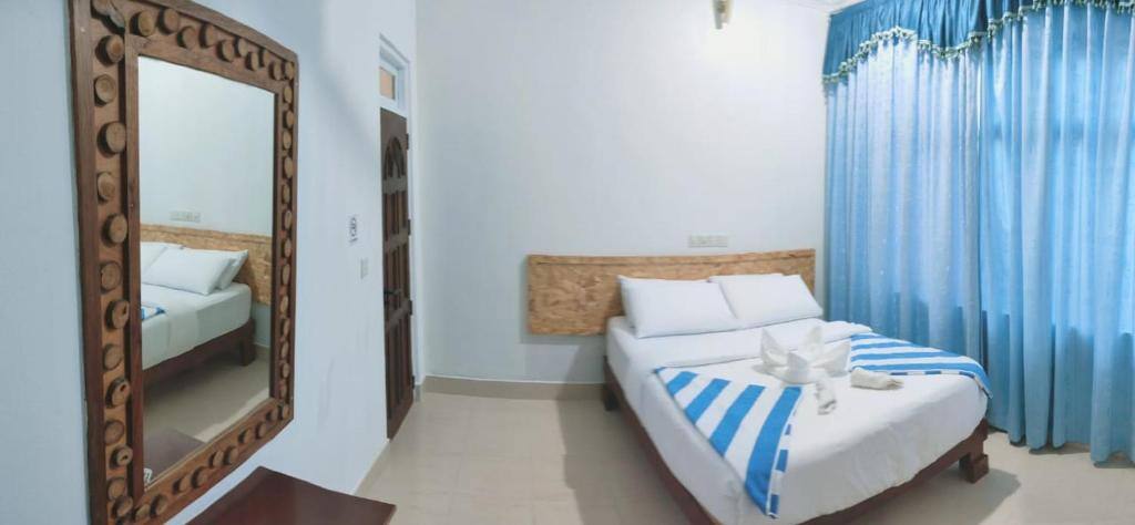 Bright guest room with double bed, mirror and blue curtains at La Isla Tropica