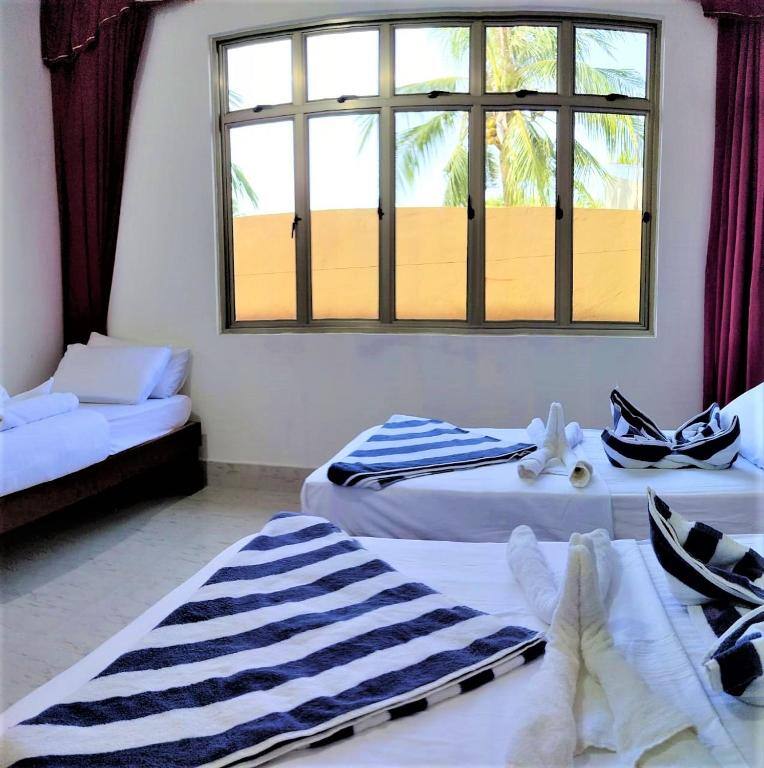 Family room with several beds and a large window overlooking palm trees